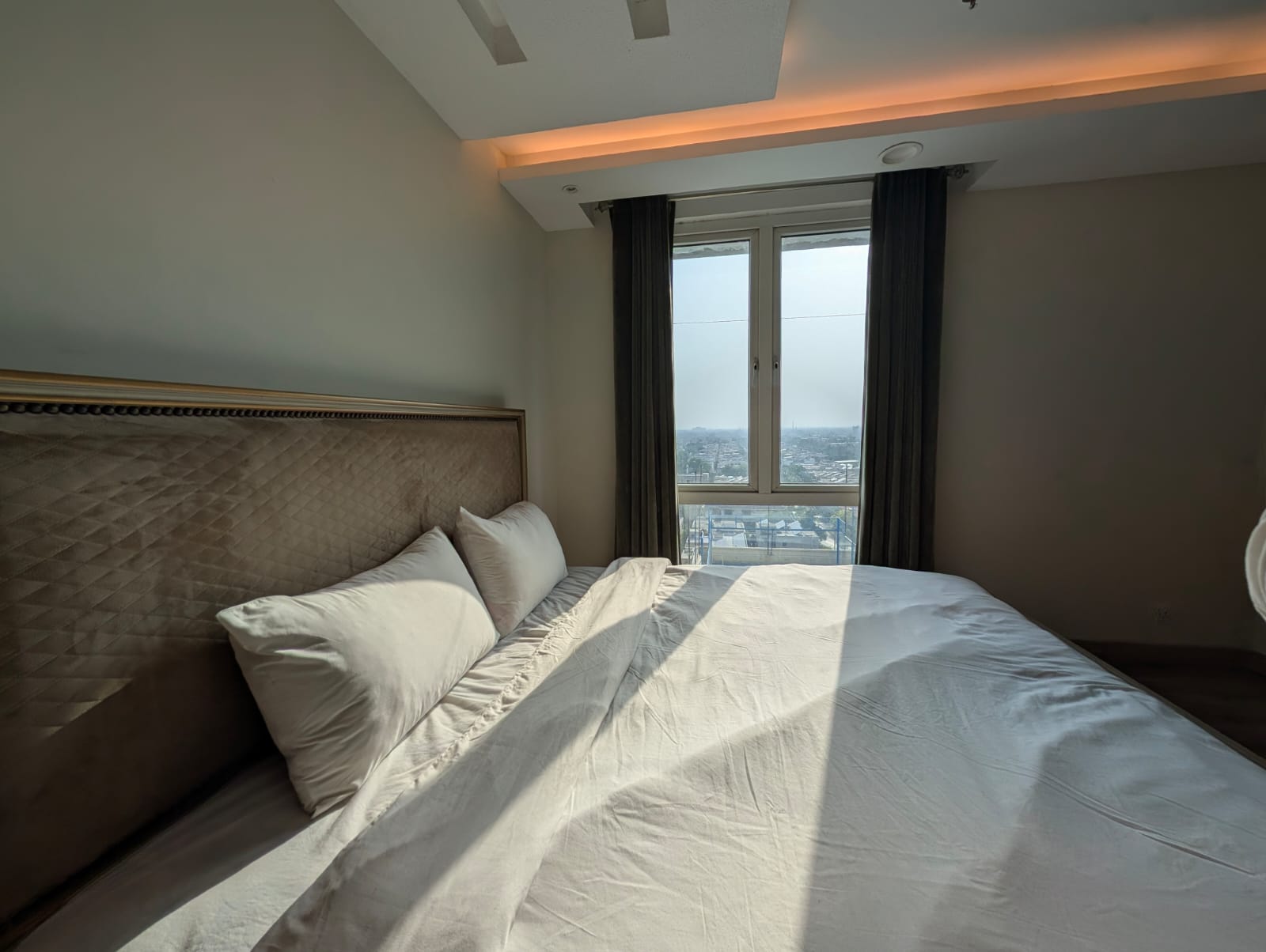 Bed with white linens next to large window